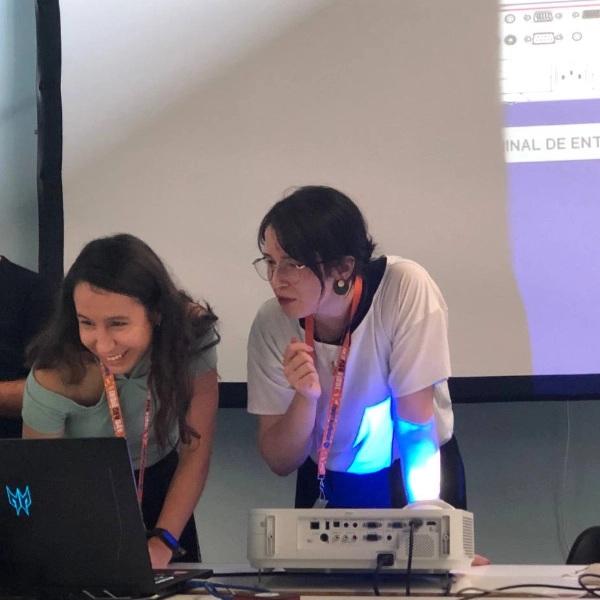 Two HappyPathLAB team members smiling while working together at a laptop during an event